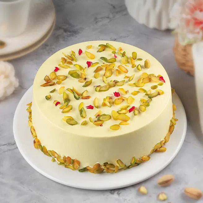 Kesar Pistachio rasmalai cake with yellow cream frosting and sliced pistachio topping
