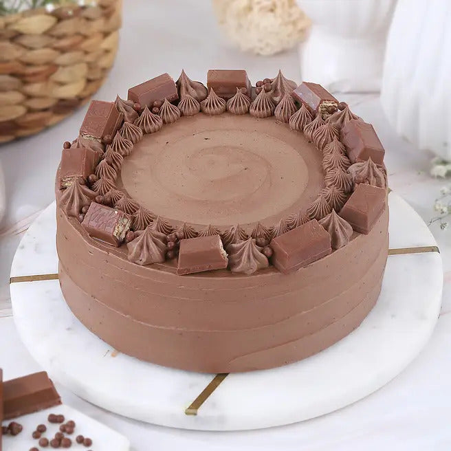 Cocoa Crunch chocolate cake with chocolate bar pieces and cream swirls