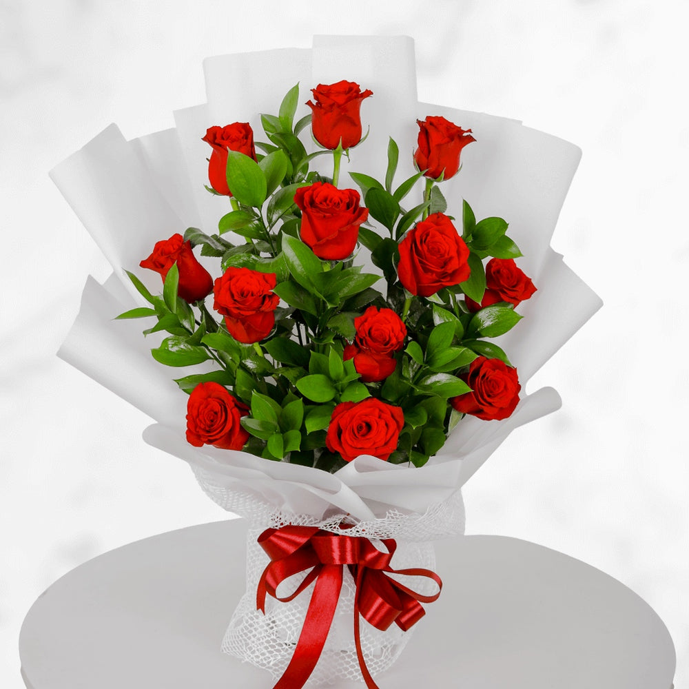 Fresh red roses bouquet in white wrapping with red ribbon for anniversary and romantic gift