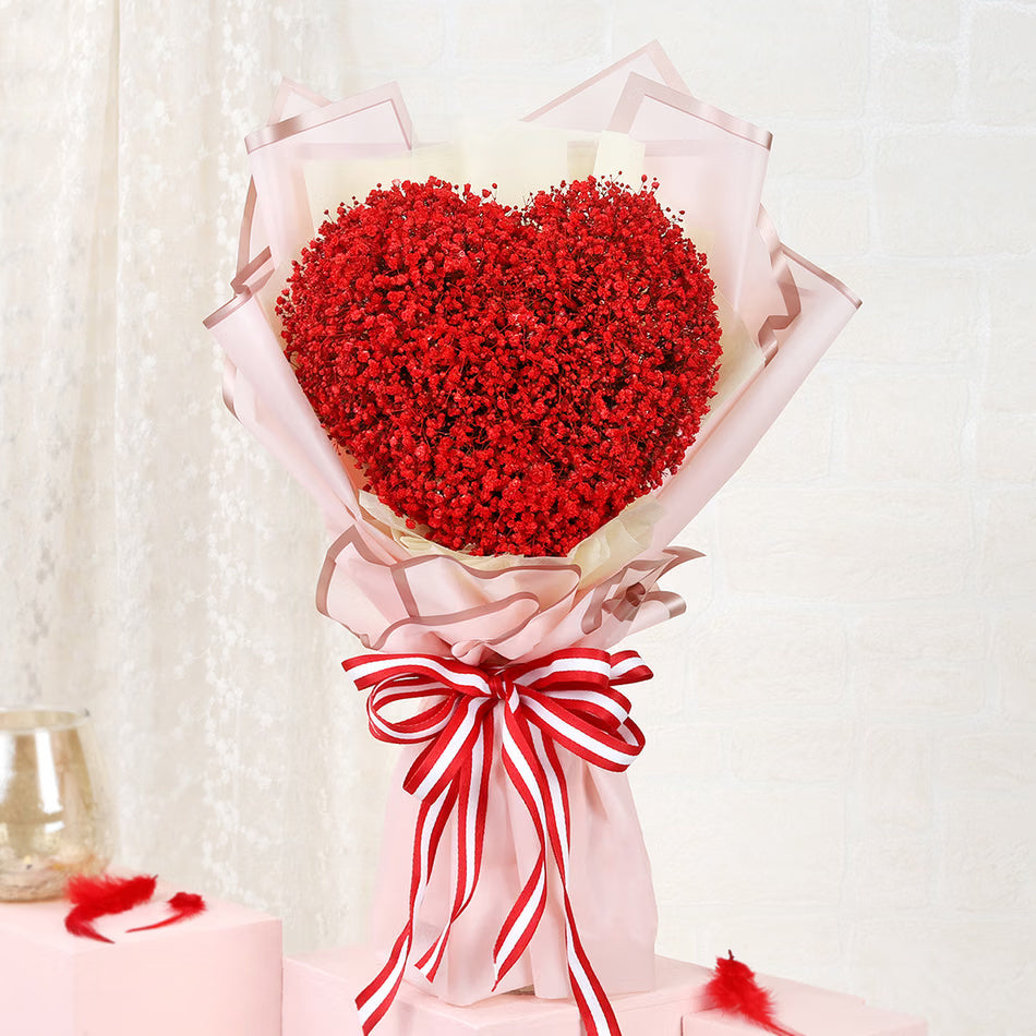 Heart-shaped red baby’s breath bouquet in pink wrapping for romantic gift delivery