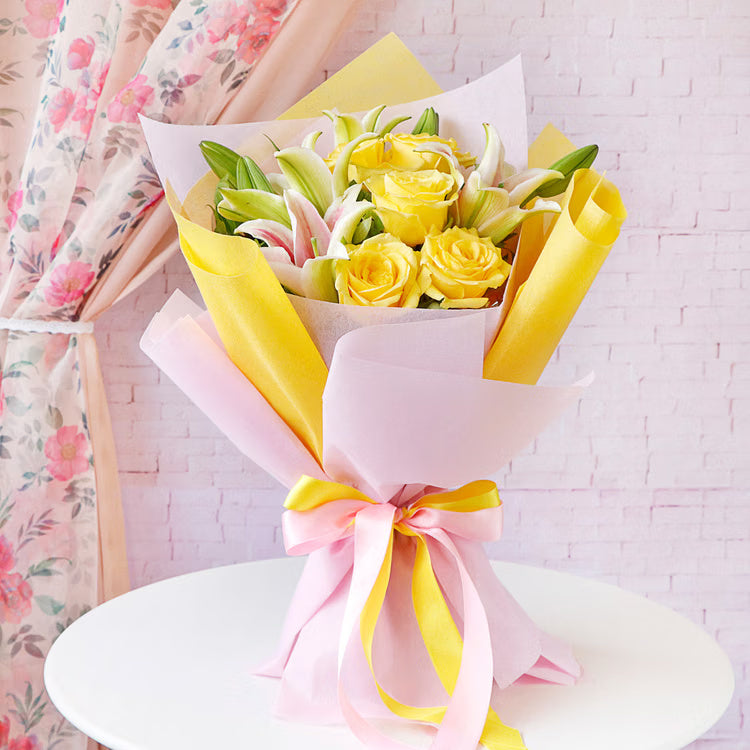 Yellow roses and lilies bouquet in pink yellow wrapping for birthday and congratulations gift