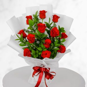 Fresh red roses bouquet in white wrapping with red ribbon for anniversary and romantic gift
