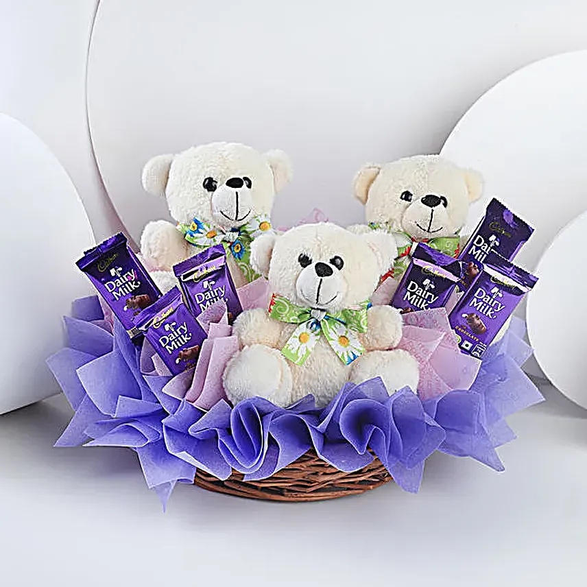 A cute basket filled with teddy bears and Dairy Milk chocolates, perfect for birthdays and sweet surprises. Three teddy bears with Dairy Milk chocolates in gift basket for birthday and kids surprise